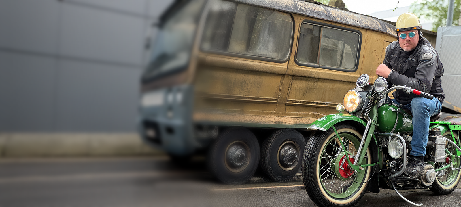 Man on a green motorcycle in front of a vintage van with a blurred background